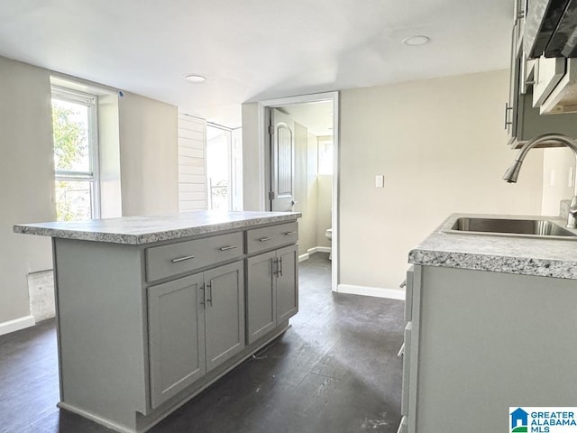 kitchen featuring dark hardwood / wood-style flooring, gray cabinets, a kitchen island, and sink