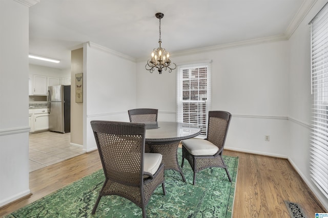 dining room with a healthy amount of sunlight, light hardwood / wood-style floors, and a notable chandelier