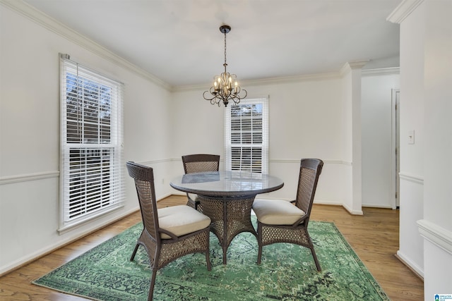 dining space with ornamental molding, light hardwood / wood-style flooring, and a notable chandelier