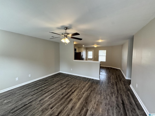 unfurnished living room featuring ceiling fan and dark wood-type flooring