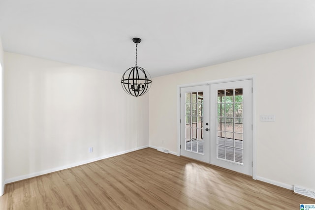 unfurnished room with light hardwood / wood-style flooring, french doors, and a notable chandelier