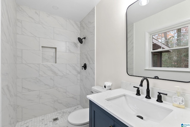 bathroom featuring vanity, toilet, and tiled shower