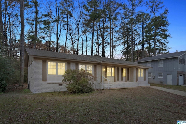 back house at dusk with a lawn and covered porch