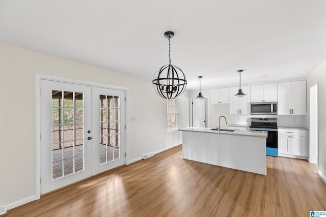 kitchen with french doors, white cabinets, an island with sink, decorative light fixtures, and stainless steel appliances