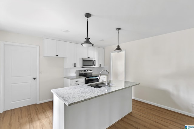 kitchen featuring light stone counters, stainless steel appliances, sink, wood-type flooring, and white cabinetry