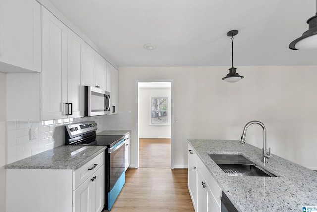 kitchen featuring hanging light fixtures, sink, white cabinets, and stainless steel appliances