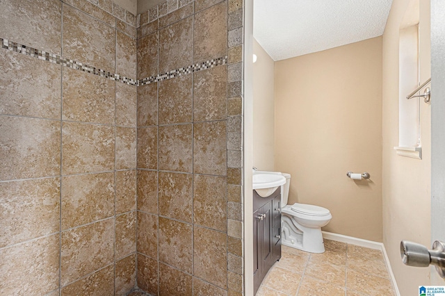 bathroom with vanity, toilet, a textured ceiling, and a tile shower