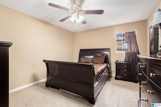 bedroom featuring ceiling fan, light colored carpet, and a textured ceiling