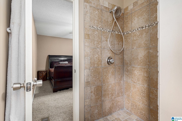 bathroom with a textured ceiling and tiled shower