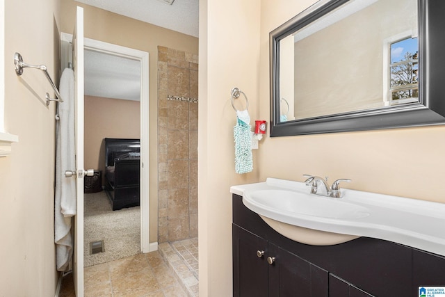 bathroom featuring tile patterned floors, vanity, a tile shower, and a textured ceiling