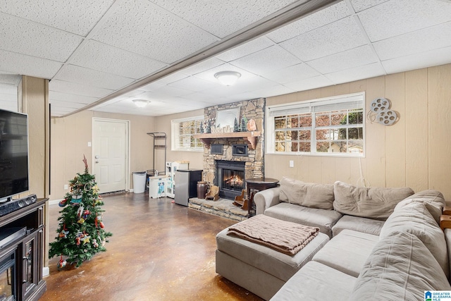 living room with a paneled ceiling, concrete flooring, a fireplace, and a wealth of natural light