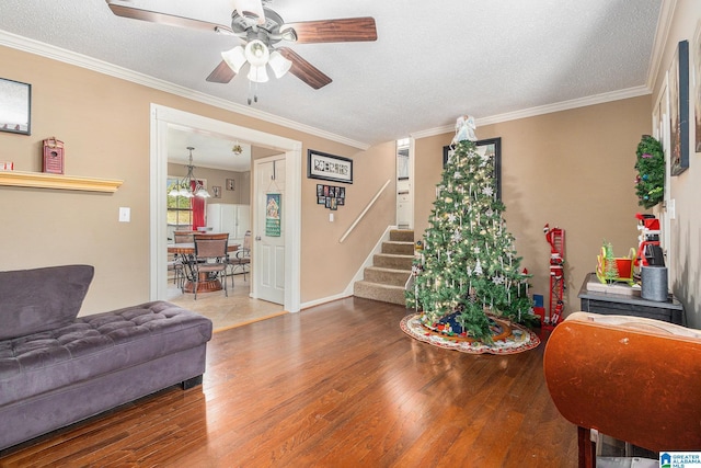 living room featuring a textured ceiling, ceiling fan, wood-type flooring, and ornamental molding