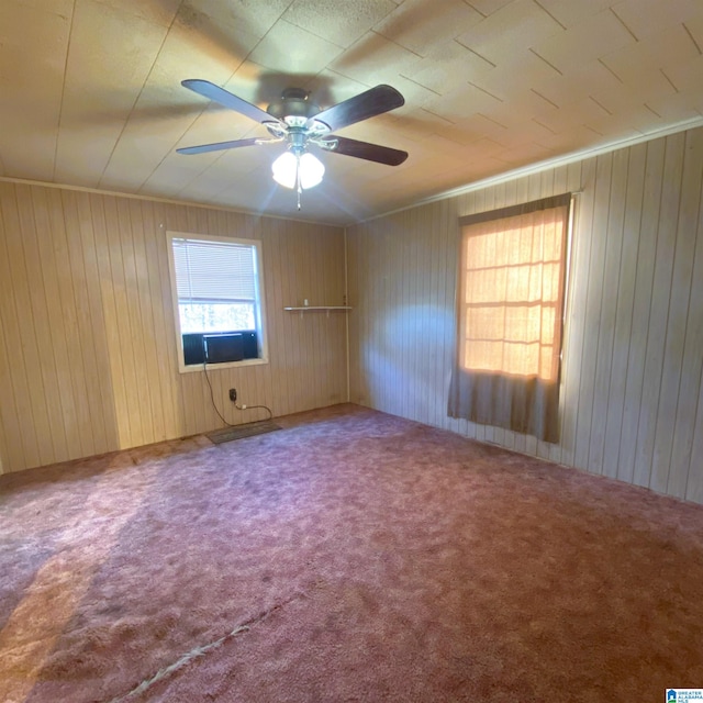 spare room with carpet, ceiling fan, and wood walls