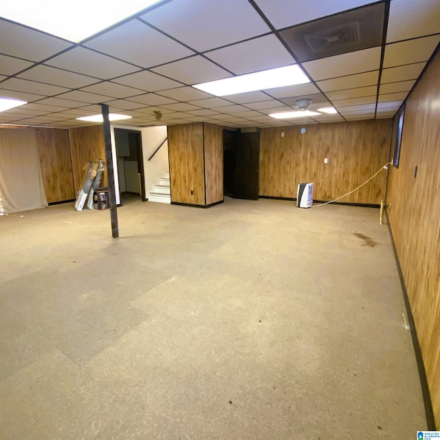 basement with a paneled ceiling and wood walls