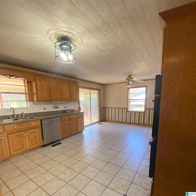 kitchen with dishwasher, wood walls, sink, ceiling fan, and light tile patterned floors