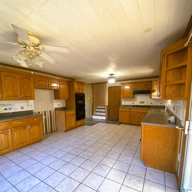 kitchen featuring ceiling fan, sink, double oven, stainless steel gas stovetop, and light tile patterned floors