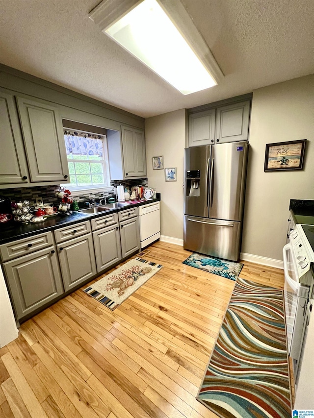 kitchen with gray cabinets, white dishwasher, light hardwood / wood-style floors, and stainless steel refrigerator with ice dispenser