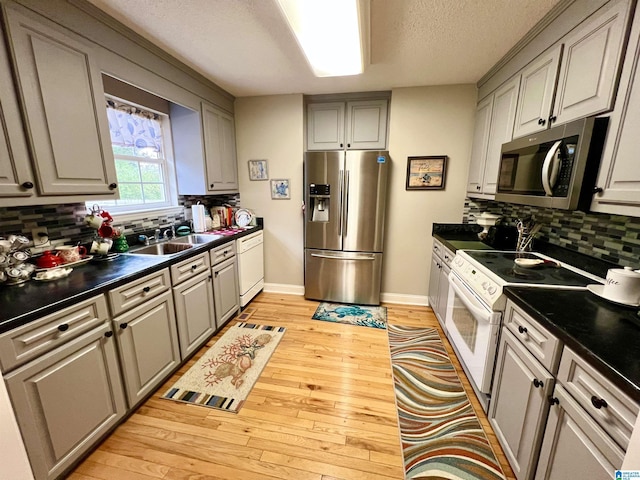 kitchen featuring backsplash, stainless steel appliances, light hardwood / wood-style floors, and sink