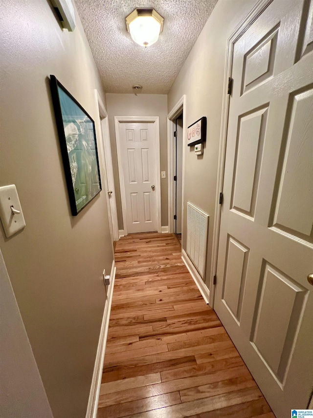 corridor featuring light hardwood / wood-style floors and a textured ceiling