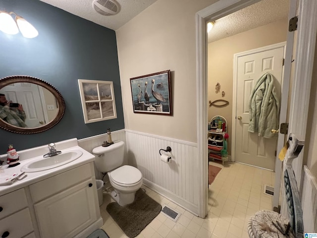 bathroom with vanity, a textured ceiling, toilet, and tile patterned flooring