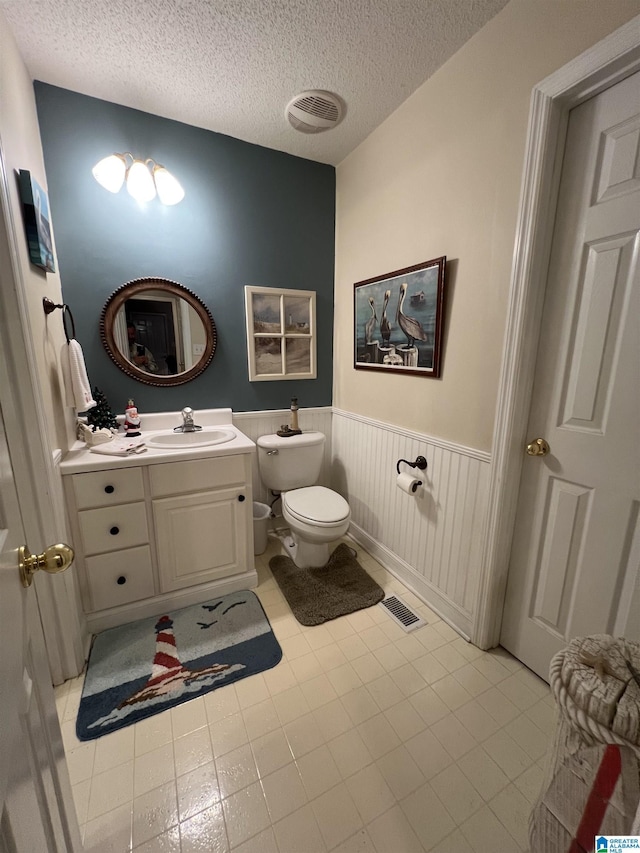 bathroom with tile patterned floors, vanity, a textured ceiling, and toilet