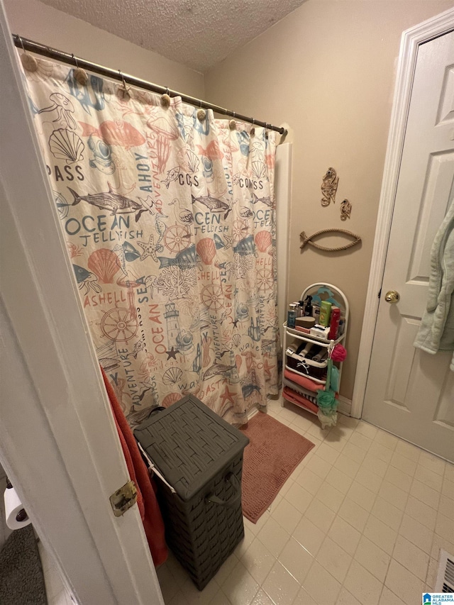 bathroom featuring a textured ceiling and tile patterned floors