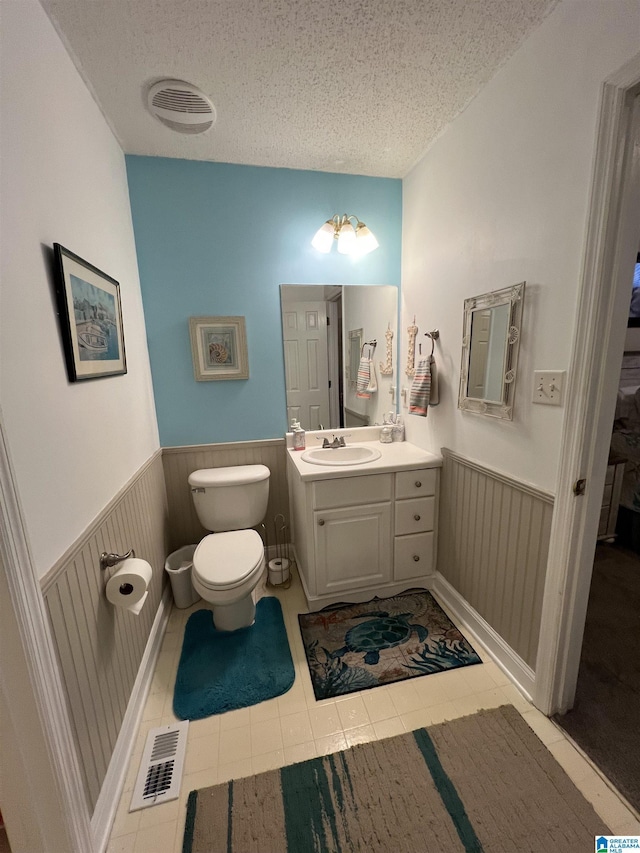 bathroom featuring toilet, vanity, a textured ceiling, and tile patterned floors