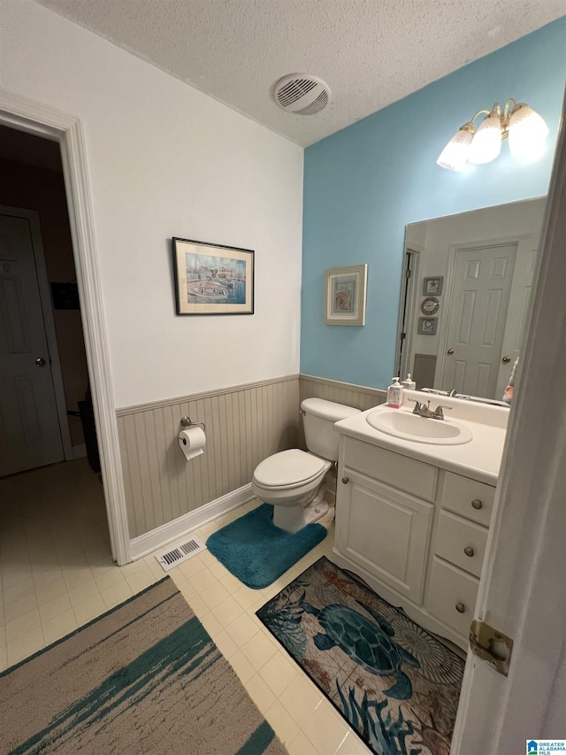 bathroom featuring vanity, a textured ceiling, tile patterned floors, and toilet