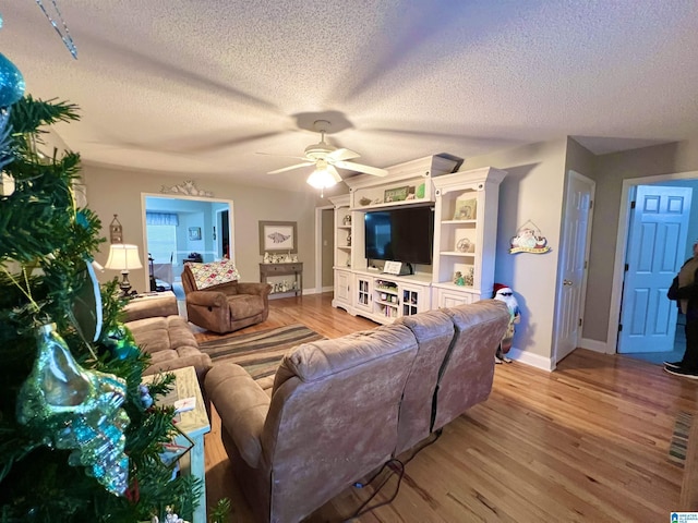 living room featuring ceiling fan, light hardwood / wood-style flooring, and a textured ceiling