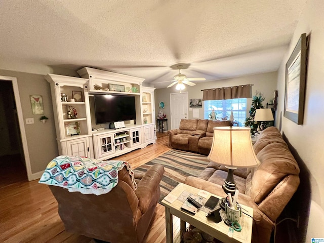 living room with ceiling fan, light hardwood / wood-style floors, and a textured ceiling