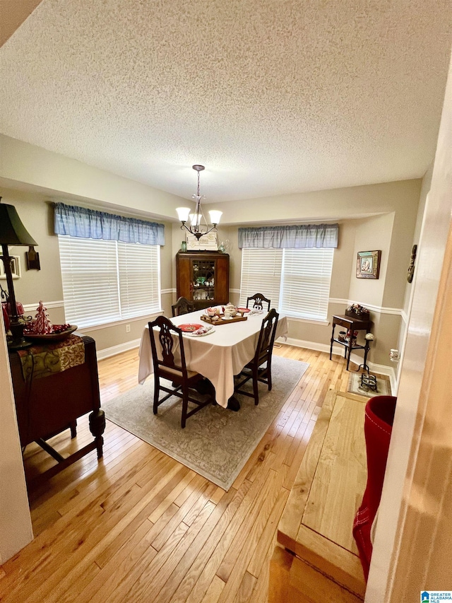 dining room with a textured ceiling, light hardwood / wood-style flooring, and a notable chandelier