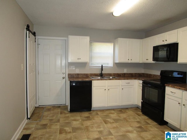 kitchen featuring sink, white cabinetry, a barn door, and black appliances