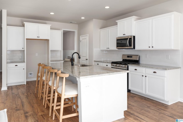 kitchen featuring sink, an island with sink, dark hardwood / wood-style floors, and appliances with stainless steel finishes