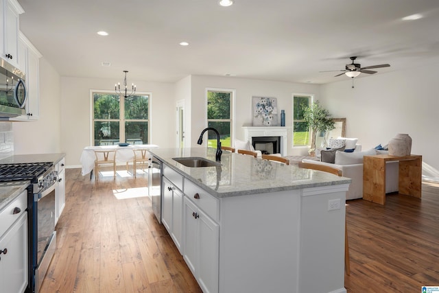 kitchen featuring sink, stainless steel appliances, light stone counters, a kitchen island with sink, and white cabinets