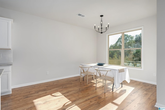 dining space featuring light wood-type flooring and a notable chandelier