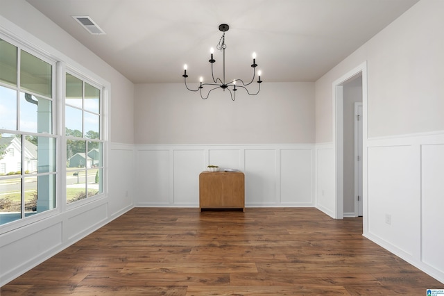 unfurnished dining area featuring a chandelier and dark wood-type flooring