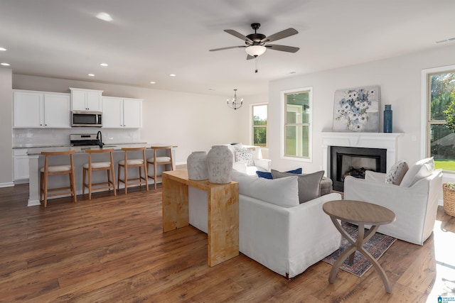 living room featuring dark hardwood / wood-style floors and ceiling fan with notable chandelier