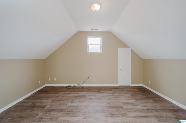 additional living space featuring lofted ceiling and light hardwood / wood-style flooring