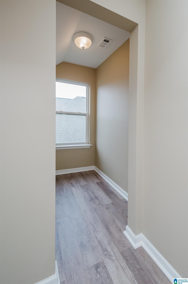 spare room featuring light wood-type flooring and vaulted ceiling