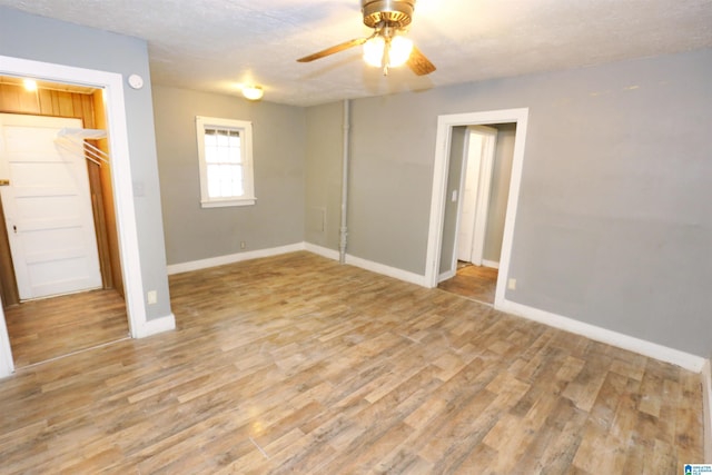 unfurnished bedroom with ceiling fan, light hardwood / wood-style flooring, a textured ceiling, a walk in closet, and a closet