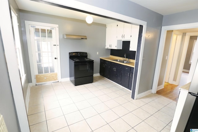 kitchen with electric range, light tile patterned flooring, white cabinets, and sink