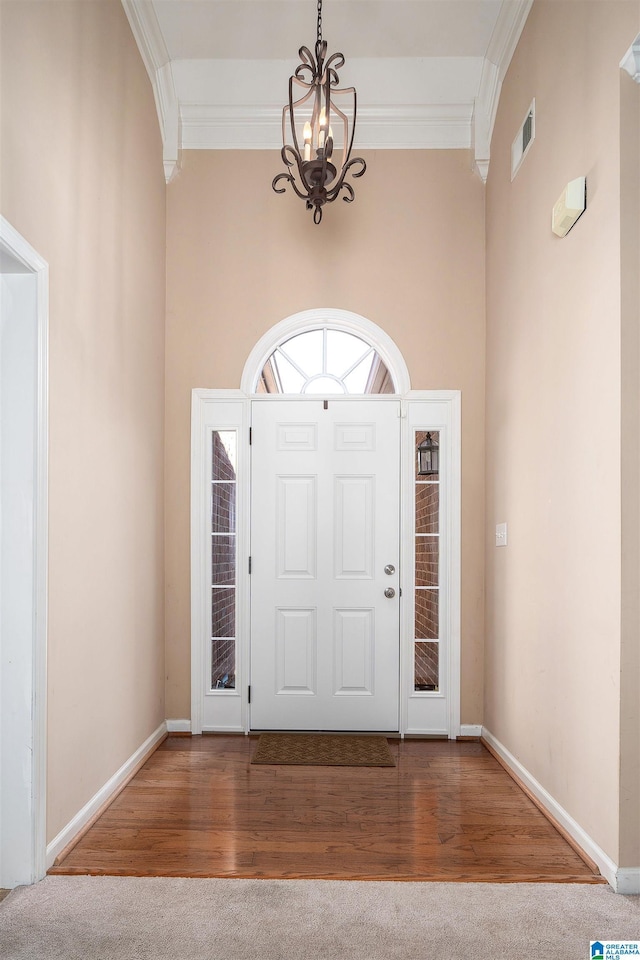 foyer entrance with hardwood / wood-style floors, a towering ceiling, and ornamental molding