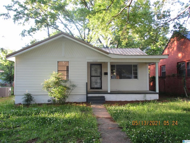 bungalow-style home featuring covered porch, a front lawn, and cooling unit