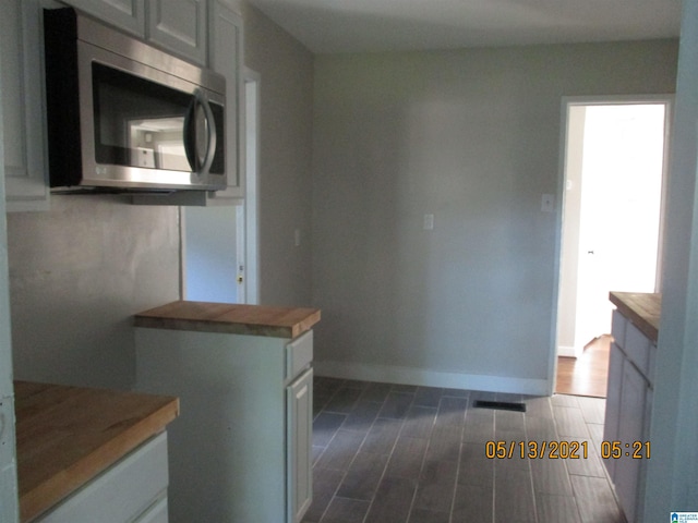 kitchen featuring butcher block countertops, white cabinetry, and dark wood-type flooring