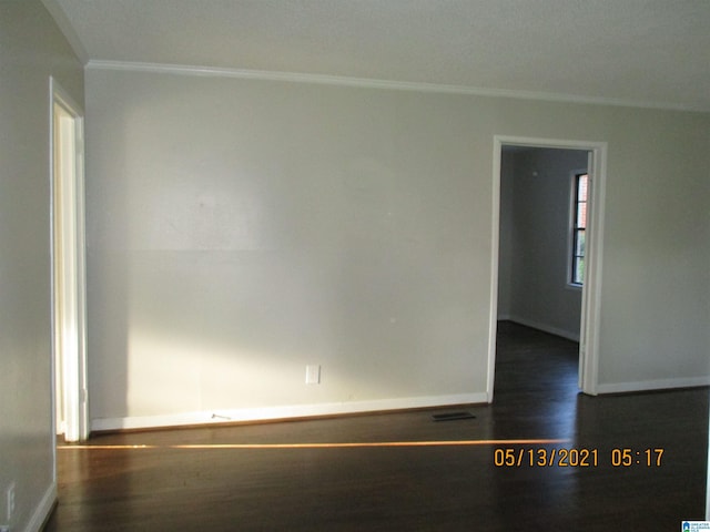 spare room featuring dark hardwood / wood-style floors and crown molding