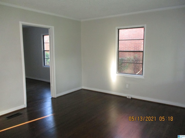 spare room with crown molding and dark wood-type flooring