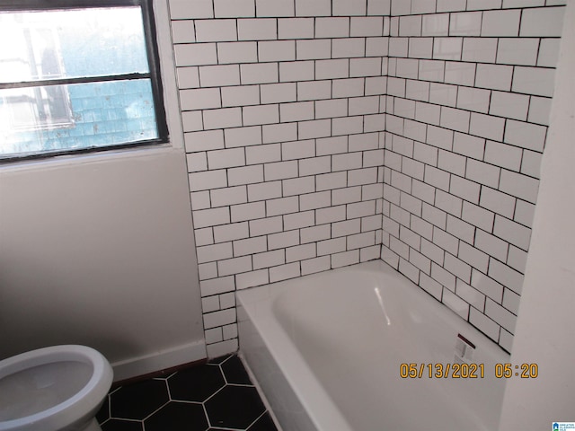 bathroom with tile patterned floors, toilet, and tiled shower / bath