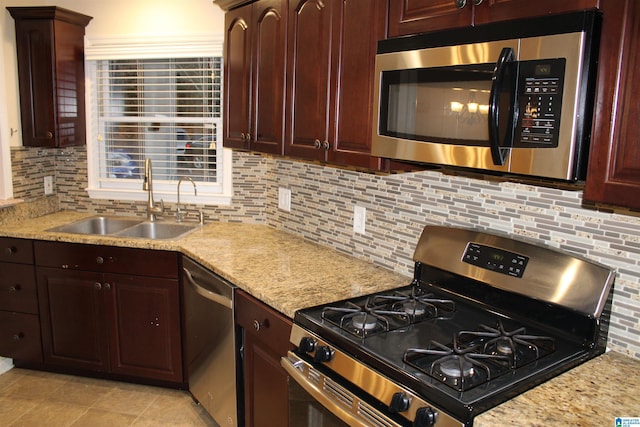 kitchen featuring light stone countertops, stainless steel appliances, tasteful backsplash, and sink