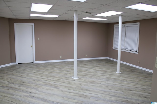 basement with a paneled ceiling and light wood-type flooring