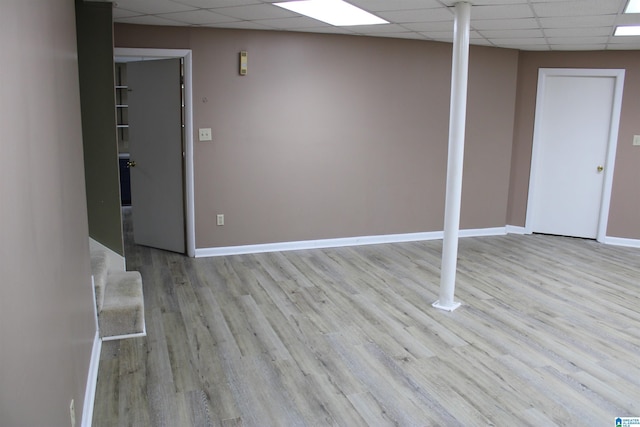 basement with a paneled ceiling and light hardwood / wood-style flooring